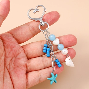 Starfish shell beaded keychain with blue beads and heart carabiner held in hand