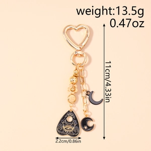 Detail of gold heart keychain with celestial moon charms and mystic enamel patterns