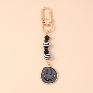 Detail of beaded keychain with gold clasp and black enamel smiley face charm