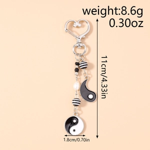 Detail view of Yin Yang keychain with black white beads and dimensions on beige background