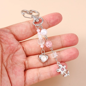 Porte-clés à perles avec cœur et fleurs en strass tenu dans la main pour sac