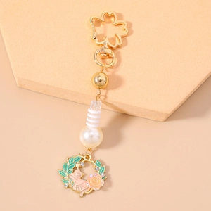Detailed close-up of golden sakura clasp keychain with cat, rose charm and white pearl