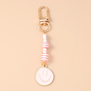 Detail of pink beaded smiley face keychain with gold lobster clasp and striped beads