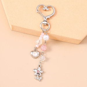 Détail du porte-clés cœur argenté avec perles roses et pendentif fleur en strass
