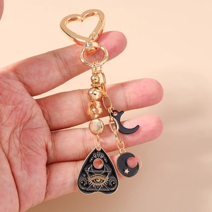 Golden heart-shaped keychain with black enamel moon and mystical eye charms