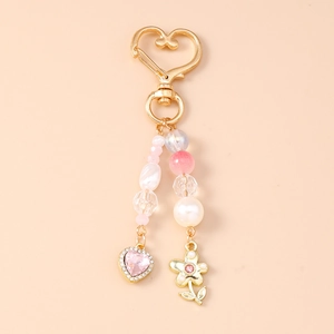 Détail de porte-clés à perles avec cristal rose en cœur et breloques de fleurs dorées