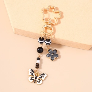 Close-up of golden cherry blossom keychain with black floral and butterfly charms