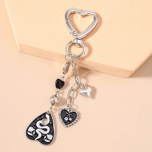 Detail of silver heart keychain with black enamel snake shield and rhinestone cherry charms