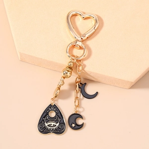 Golden heart-shaped keychain with black enamel planchette and crescent moon charms