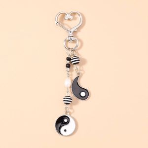 Detail of Yin Yang keychain featuring heart clasp, enamel pendants, and decorative pearls
