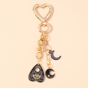Detailed macro view of golden mystic keychain featuring black enamel heart and moon charms