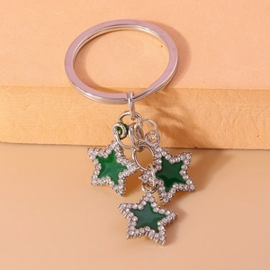 Detail of silver keychain with green enamel stars and white rhinestones on warm background