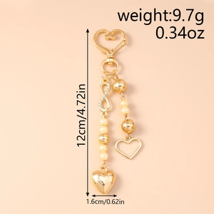 Detail of golden heart keychain with infinity symbol, pearls and sparkling rhinestones