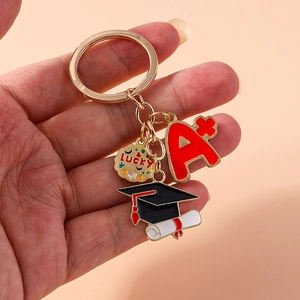 Golden graduation cap keychain with A+ and Lucky charms on a minimalist background