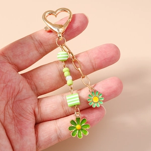 Fashionable daisy keychain with green striped beads and golden heart hook in hand