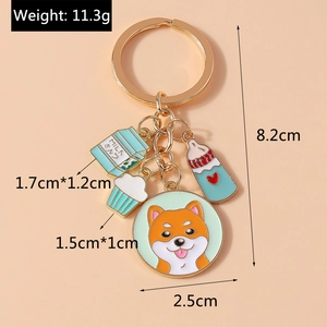 Détail du porte-clés doré avec Shiba Inu, brique de lait et charmes de cupcakes