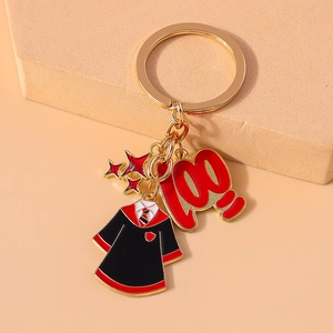 Macro shot of gold-plated keychain with graduation robe, red 100 digit and star charms