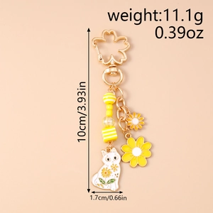 Nahaufnahme gelber Katzen-Schlüsselanhänger mit Sonnenblumen und Gold-Kirschblüte