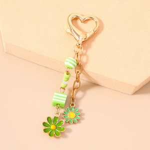 Detail of heart-shaped gold carabiner keychain with green daisy pendants and beads