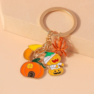 Detailed macro view of Halloween pumpkin house and spider charms on gold metal keychain