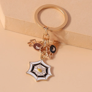 Close-up of Halloween keychain with gold ring and enamel spider and cobweb charms