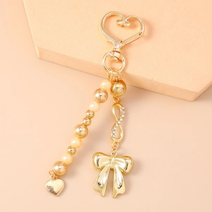 Detail of gold bow pendant and rhinestone infinity symbol on a pearl beaded keychain