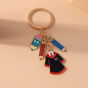 Golden keychain with colorful pencils and academic robe pendant on warm background