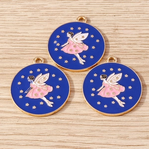 Three circular enamel fairy charms with golden stars on a natural wood surface background