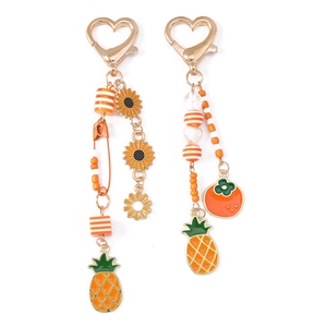 Detailansicht der Sonnenblumen- und Ananas-Anhänger mit goldenem Herz-Karabiner