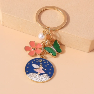 Détail d'un porte-clés fée fleurie avec anneau doré, perle et breloque fleur rose élégante