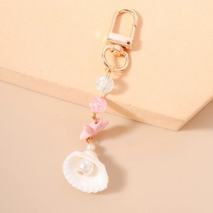 Close-up of ocean-themed keychain featuring pink starfish and pearl inside a white shell