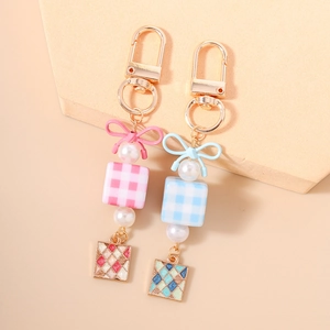 Macaron pastel keychain with checkered cube, bow and pearl charms on geometric stand