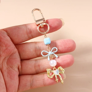 Détail du porte-clés avec nœud bleu ciel, perles et fermoir mousqueton en métal doré