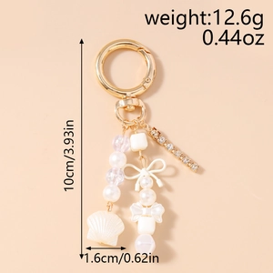 Détail du porte-clés avec chaîne en strass, nœuds blancs et pendentifs de nacre perle