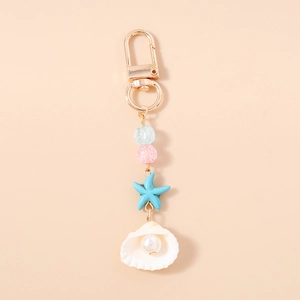 Detail view of ocean-themed keychain with blue starfish, white shell and faux pearl