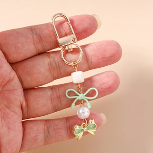 Détail d'un porte-clés perlé avec nœud menthe et pendentif papillon doré pour sac à main