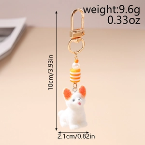 Vue macro d'un porte-clés chien en peluche blanc avec oreilles orange et fermoir doré