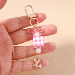 Detail of keychain with pink checkered cube, pearl beads, and butterfly bow design