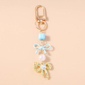 Détail de porte-clés perles avec nœud bleu et pendentif papillon cœur doré brillant