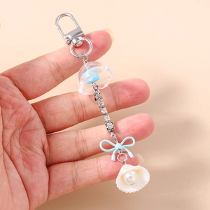 Détail du pendentif coquillage avec perle, chaîne strass et nœud bleu sur le porte-clés