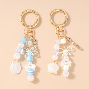 Porte-clés tendance avec chaîne strass, perles, nœud et pendentif coquillage en deux tons