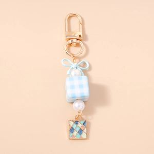 Detail of blue bow, pearl beads, and checkered cube on fashion enamel keychain charm