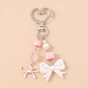 Detail of pink and pearl white beaded bag charm with heart hook and ribbon bows