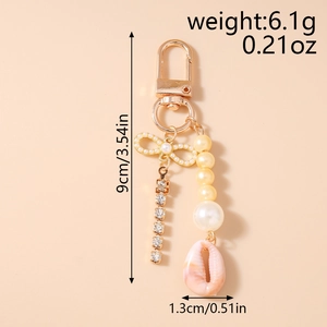 Detail of beaded keychain featuring rhinestone chain, pearl bow and pink seashell pendant