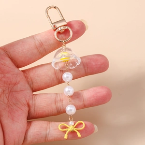 Détail d'un porte-clés doré avec cloche en acrylique, perles et nœud jaune élégant
