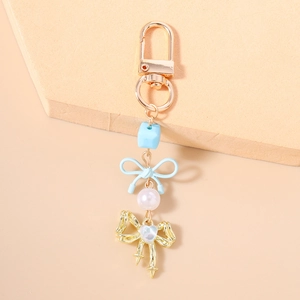Détail du porte-clés en perles avec nœud bleu et pendentif papillon doré ajouré