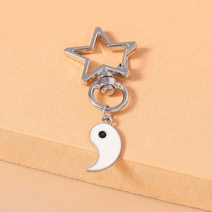 Détail du fermoir métallique en étoile et du pendentif goutte yin yang en émail blanc