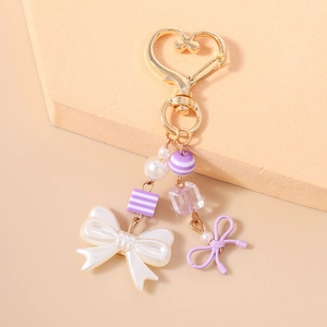 Macro view of gold heart clasp with purple striped bead and white satin bow pendant