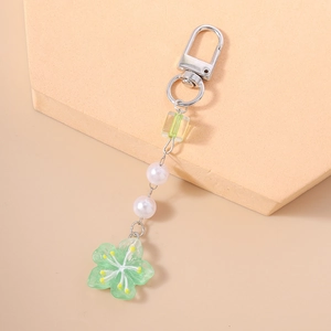 Detail of beaded floral keychain with green resin flower and pearl-like charms