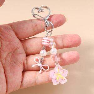 Dettaglio ciondolo per borsa con fiori di ciliegio moschettone a cuore e perline